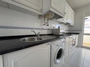 A modern kitchen with a double sink, a microwave, and a built-in washing machine. - Armação DE Pêra Central 3 by Homing (Silves)