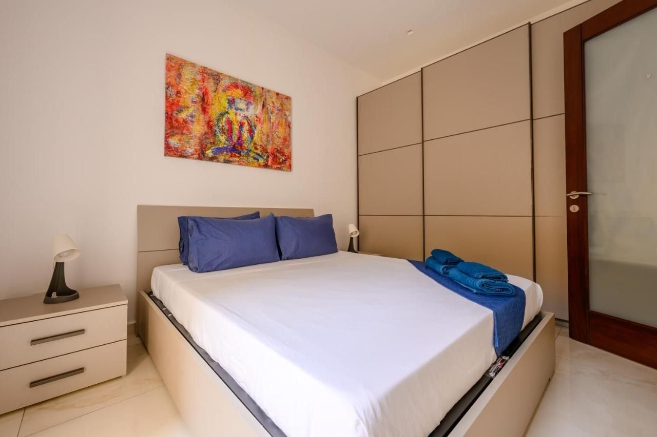 A modern bedroom with a bed, a nightstand, a painting, and a sliding door.