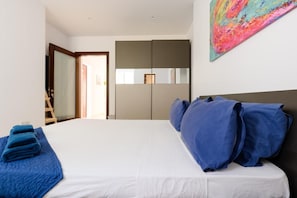 A bedroom with a bed, a wardrobe, and a colorful abstract painting.