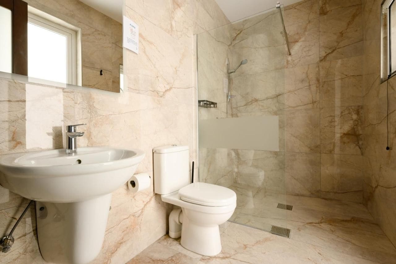 Un baño con lavamanos, inodoro y ducha de mármol.