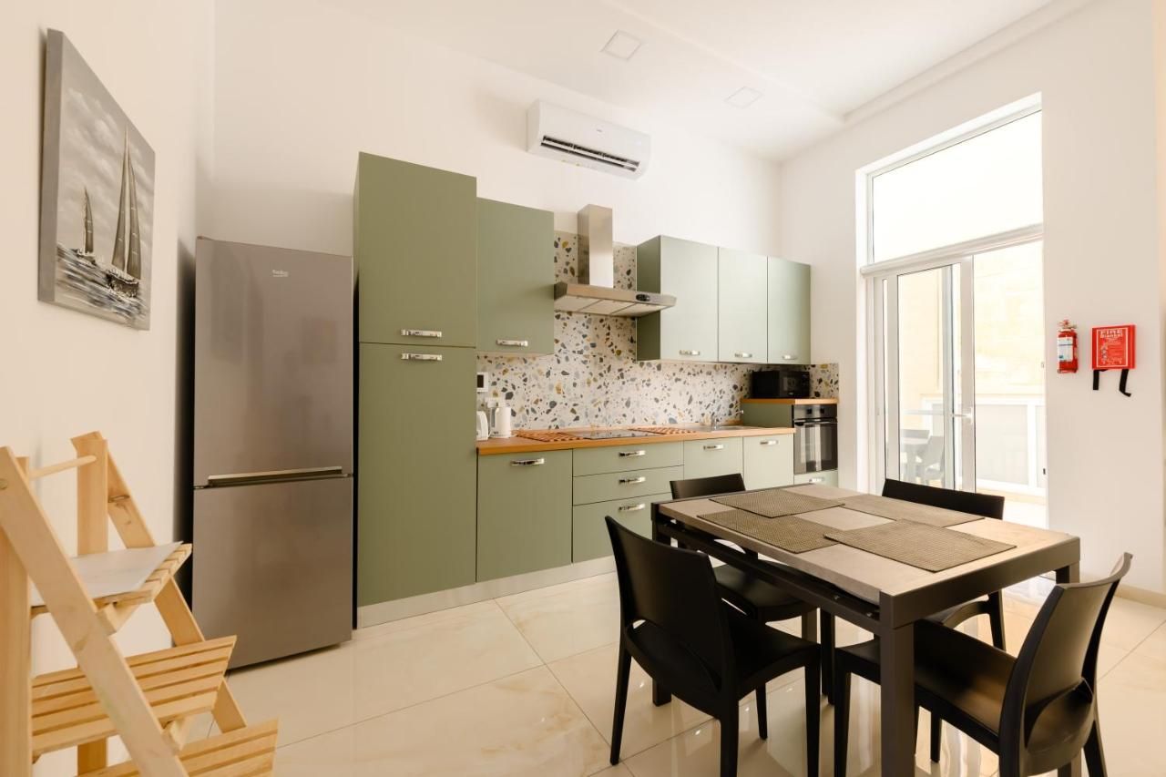 A modern kitchen with a built-in refrigerator, a stove, and a dining area with a table and chairs.