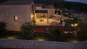 Uma casa de pedra com um pátio, área de estar ao ar livre e vista para a paisagem circundante.