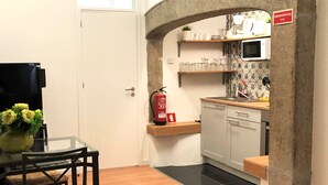 A compact kitchen with a microwave, a fire extinguisher, and a small countertop. - SJ1E + SJ1D Spacious & Comfortable | 2 Apts | A/C (Lisboa ciudad)