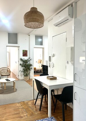 A modern interior with a dining table, chairs, a hanging light fixture, a potted plant, and a white cabinet. - SJ2D+SJ2E Spacious & Central! | 2 Apts | A/C (Lisboa ciudad)