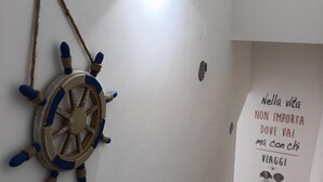 A staircase with a wall-mounted ship's wheel and a sign with Italian text.