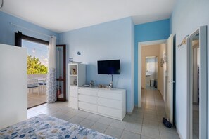 Een slaapkamer met een bed, een dressoir, een televisie en uitzicht op het landschap.