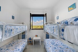 Een kamer met stapelbedden, een klein tafeltje en een raam met uitzicht op de lucht en het landschap.