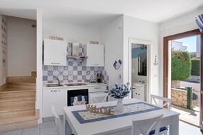 Een moderne keuken met witte kasten, een blauw betegelde muur en een eethoek met een 'WELCOME' bord.