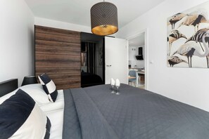 Ein modernes Schlafzimmer mit einem großen Bett, einer Wandpaneele aus Holz, einer hängenden Leuchte und einem Wandbild von Flamingos.