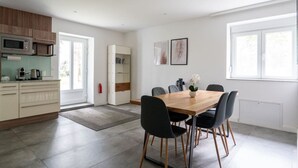 Una cocina moderna con comedor, que incluye una mesa de madera y sillas negras, un armario blanco y un microondas.