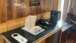 Eine Holztresen mit Kaffeemaschine, Telefon und einem kleinen Tisch mit Taschentuchbox und Tasse.