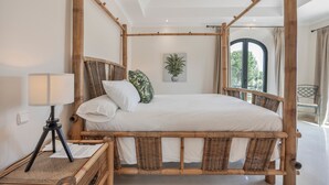 A four-poster bed with a white bedspread, a lamp on a side table, and a potted plant on the wall. - Villa 'Arcos Golf Jacaranda 11' with Mountain View, Wi-Fi and Air Conditioning (Arcos de la Frontera)
