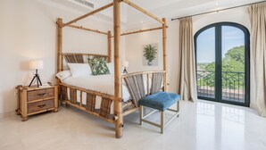 A four-poster bed with a bench, bedside tables, a potted plant, and a balcony with a view. - Villa 'Arcos Golf Jacaranda 11' with Mountain View, Wi-Fi and Air Conditioning (Arcos de la Frontera)
