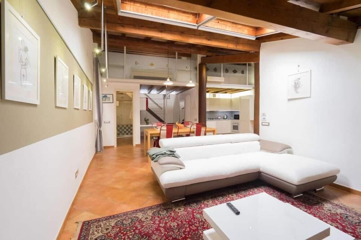 A modern living room with a sectional sofa, a coffee table, and a kitchen in the background.