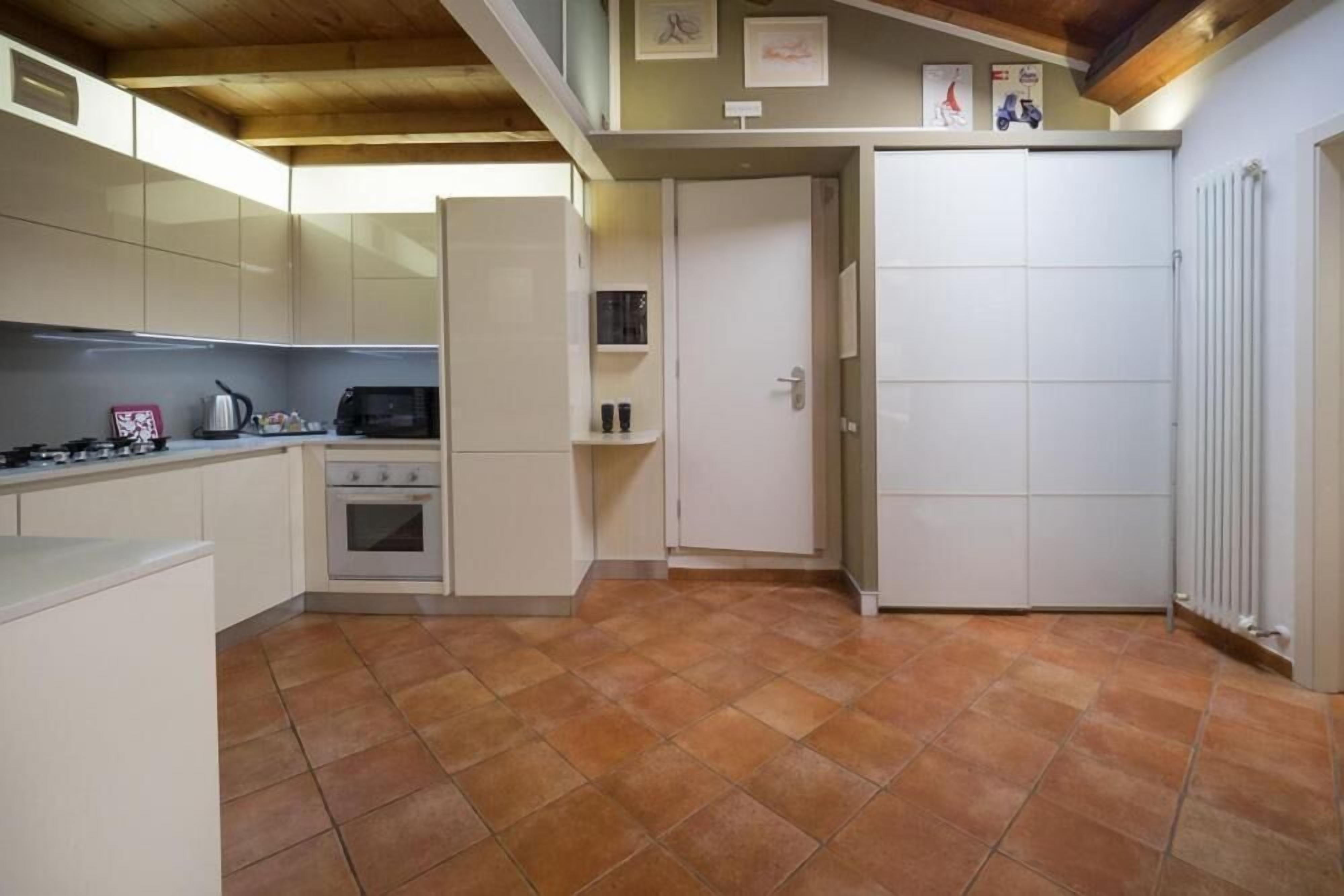 Una cocina compacta con armarios blancos, estufa y microondas.