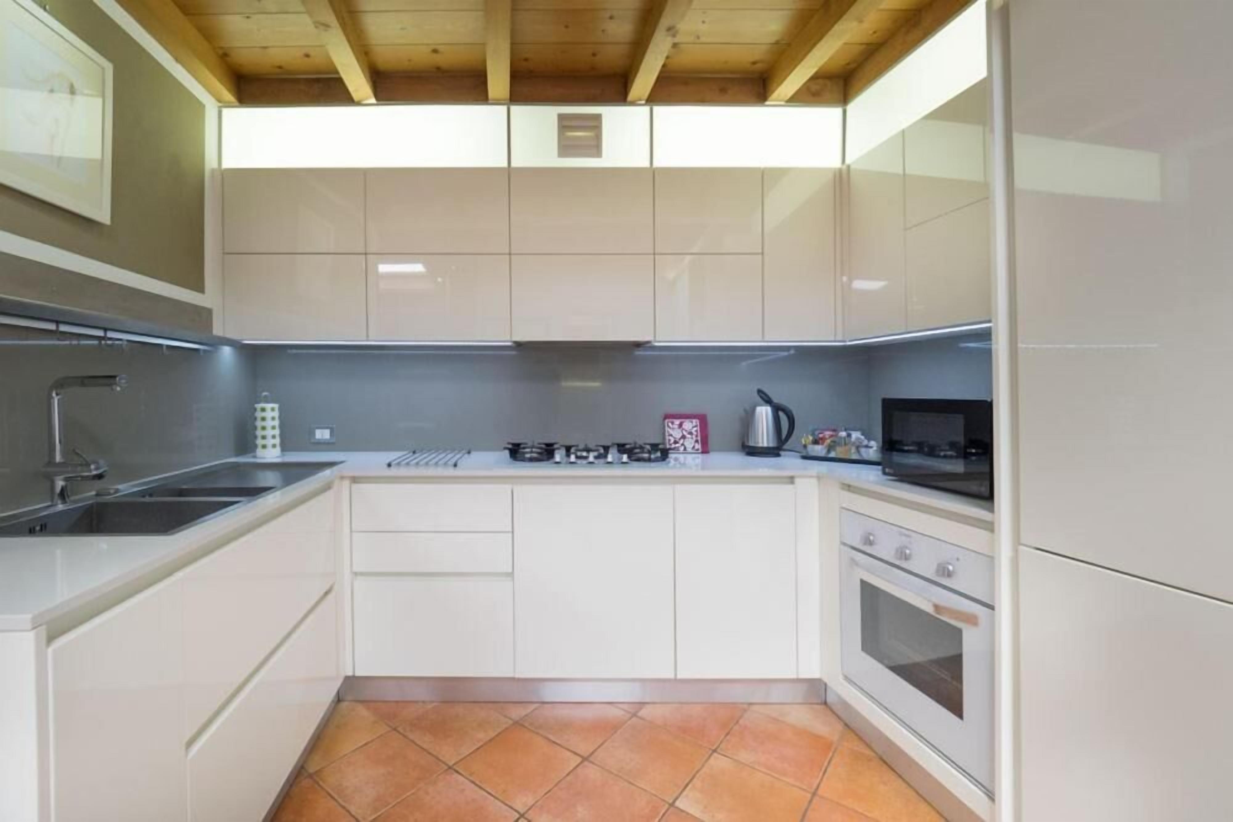 Una cocina moderna con armarios blancos, una estufa a gas, un microondas y un fregadero.