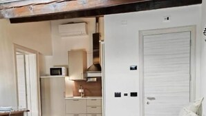 A compact living space with a kitchenette, a dining area, and a sofa. - Alkimia Apartments (Ferrara)