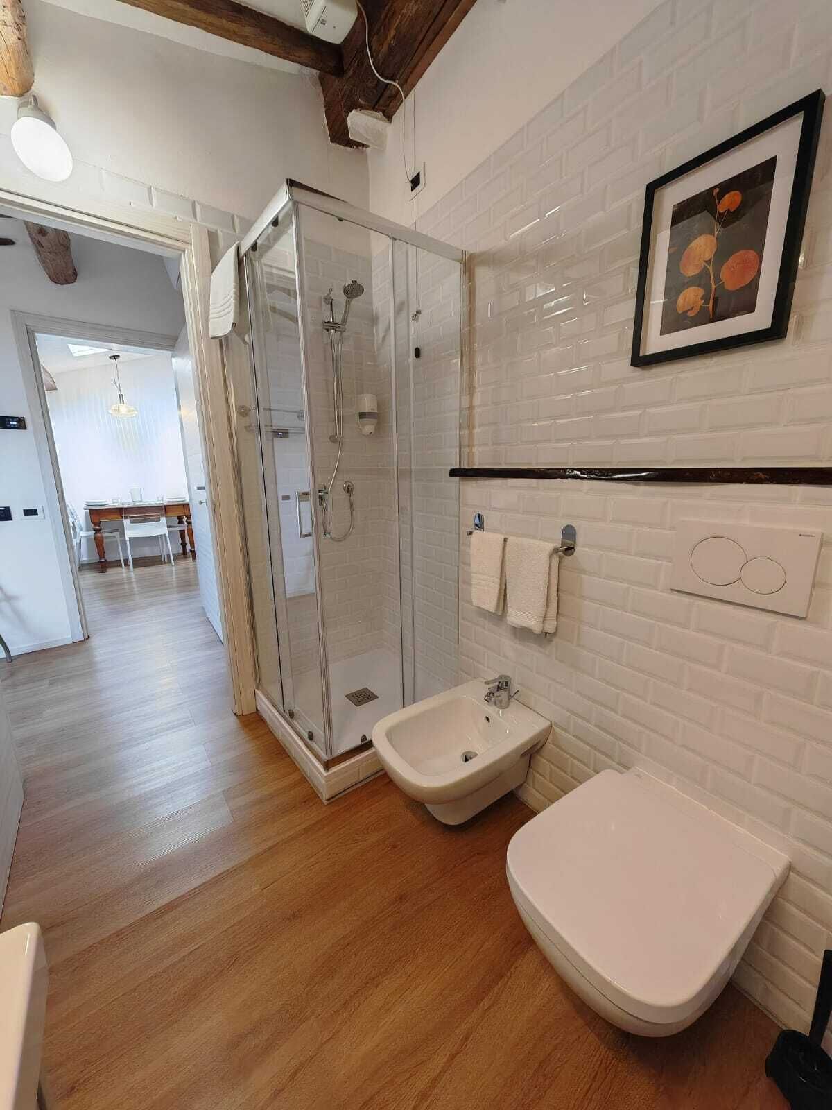 A modern bathroom with a glass-enclosed shower, a white sink, and a toilet.
