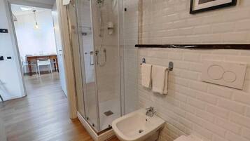A modern bathroom with a glass-enclosed shower, a white sink, and a toilet.