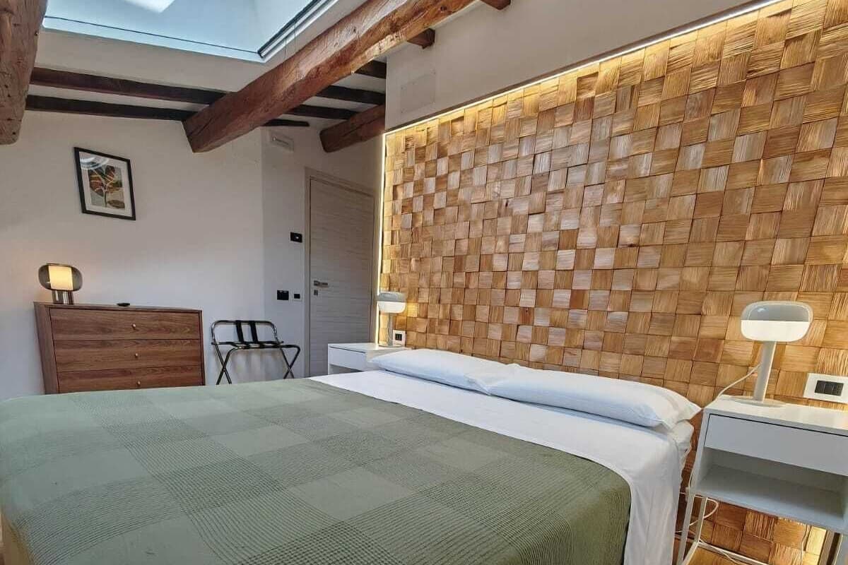 A bedroom with a large bed, wooden ceiling beams, a woven headboard, and a skylight.