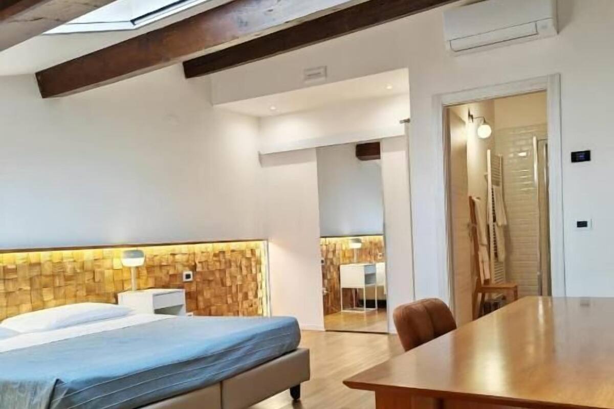 A modern bedroom with a wooden ceiling, a bed, a wooden dining table, and a skylight.