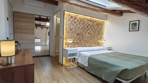 A bedroom with a wooden ceiling, a bed, a bedside table, a lamp, and a wardrobe. - Alkimia Apartments (Ferrara)