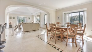 Un amplio espacio habitable con una mesa de comedor, sillas, un sofá y un ventanal grande.