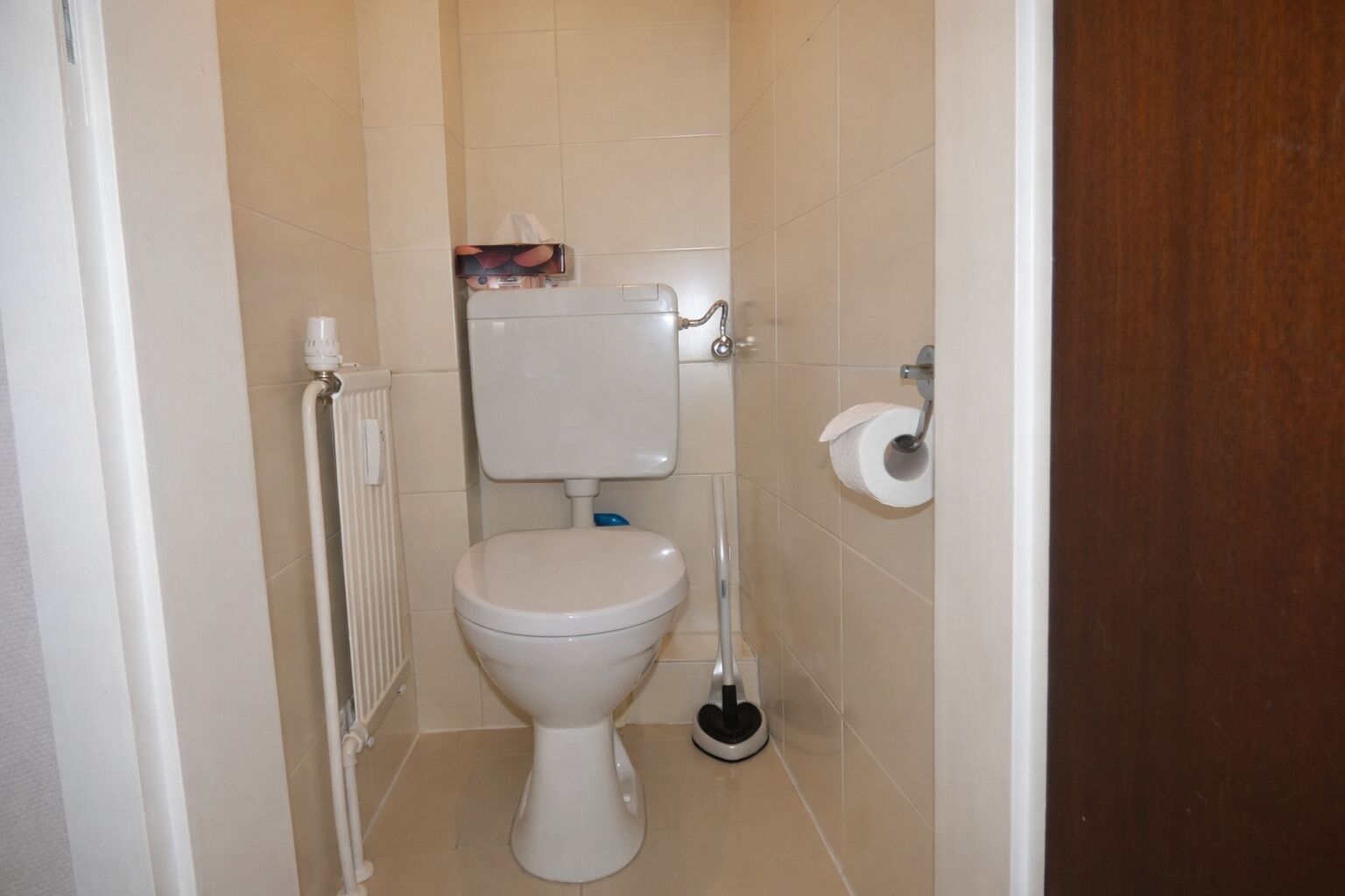 Une petite salle de bain propre, équipée de toilettes, d’un porte-rouleau de papier toilette et d’un bidet.