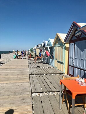 A wooden pier leading to colorful beach huts with a clear sky above. - Vacation home "LES FOUGÈRES" near Baie de Somme ideal for families (Ochancourt)