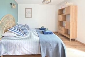 A bedroom with a bed, a bedside table, a wall-mounted lamp, a framed artwork, and a wooden wardrobe. - "LES FOUGÈRES" Vacation Home near Baie de Somme, ideal for families (Ochancourt)
