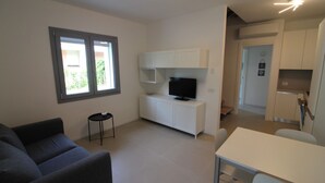 Un apartamento moderno y bien iluminado con sala de estar, mesa de comedor y kitchenette.