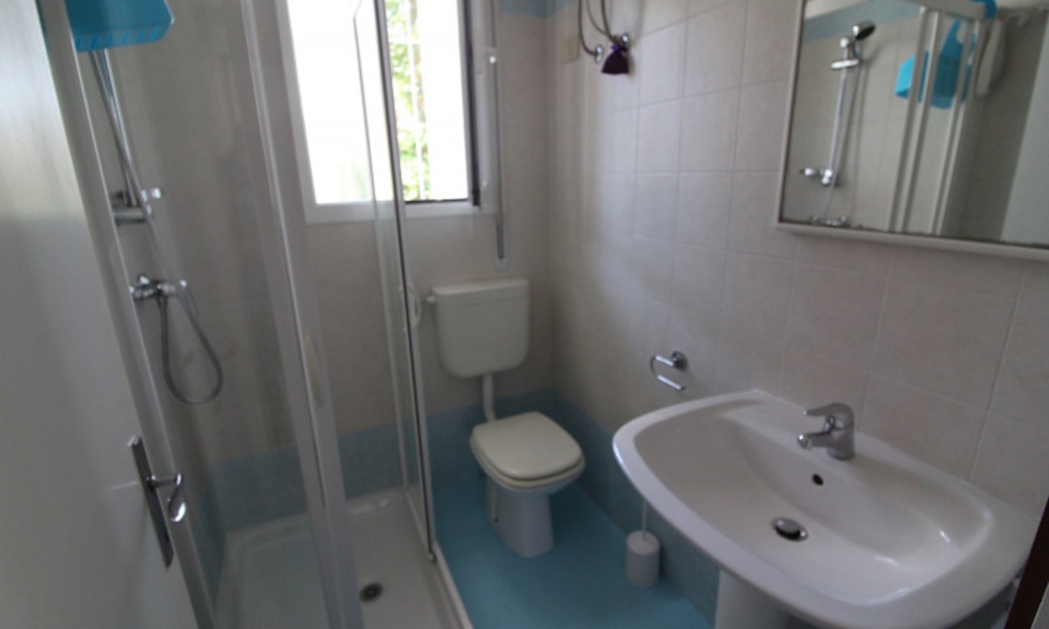 Een badkamer met een douchecabine van glas, een toilet en een wastafel.
