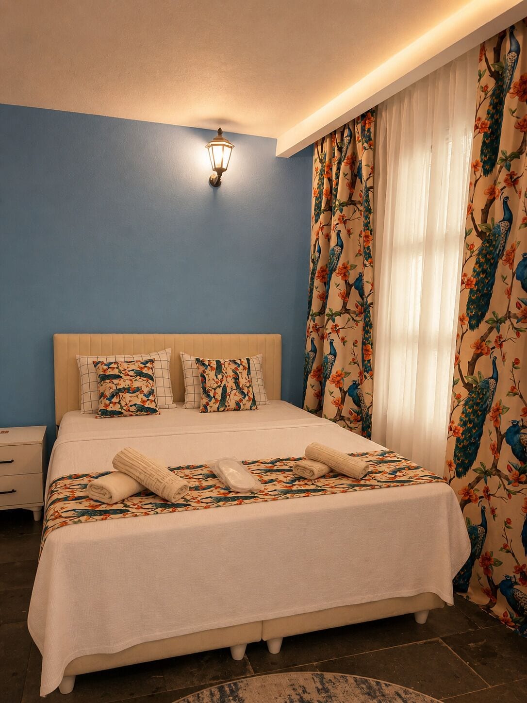 Un dormitorio con una cama, almohadas, una mesita de noche y una lámpara de pared.