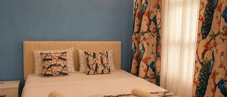 A bedroom with a bed, pillows, a nightstand, and a wall-mounted light.