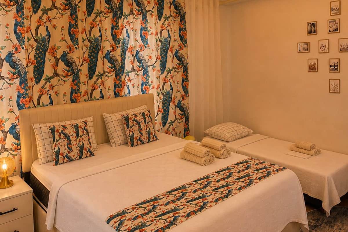 Une chambre d’hôtel avec un grand lit, deux petits lits, un lustre et un mur orné de tableaux.