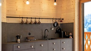 Una cocina con techo de madera, utensilios colgantes, un lavabo, armarios y vistas al exterior.