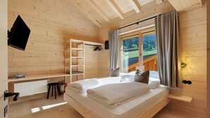 Una habitación de cabaña de madera con una cama, estante, radiador y ventana con cortinas.