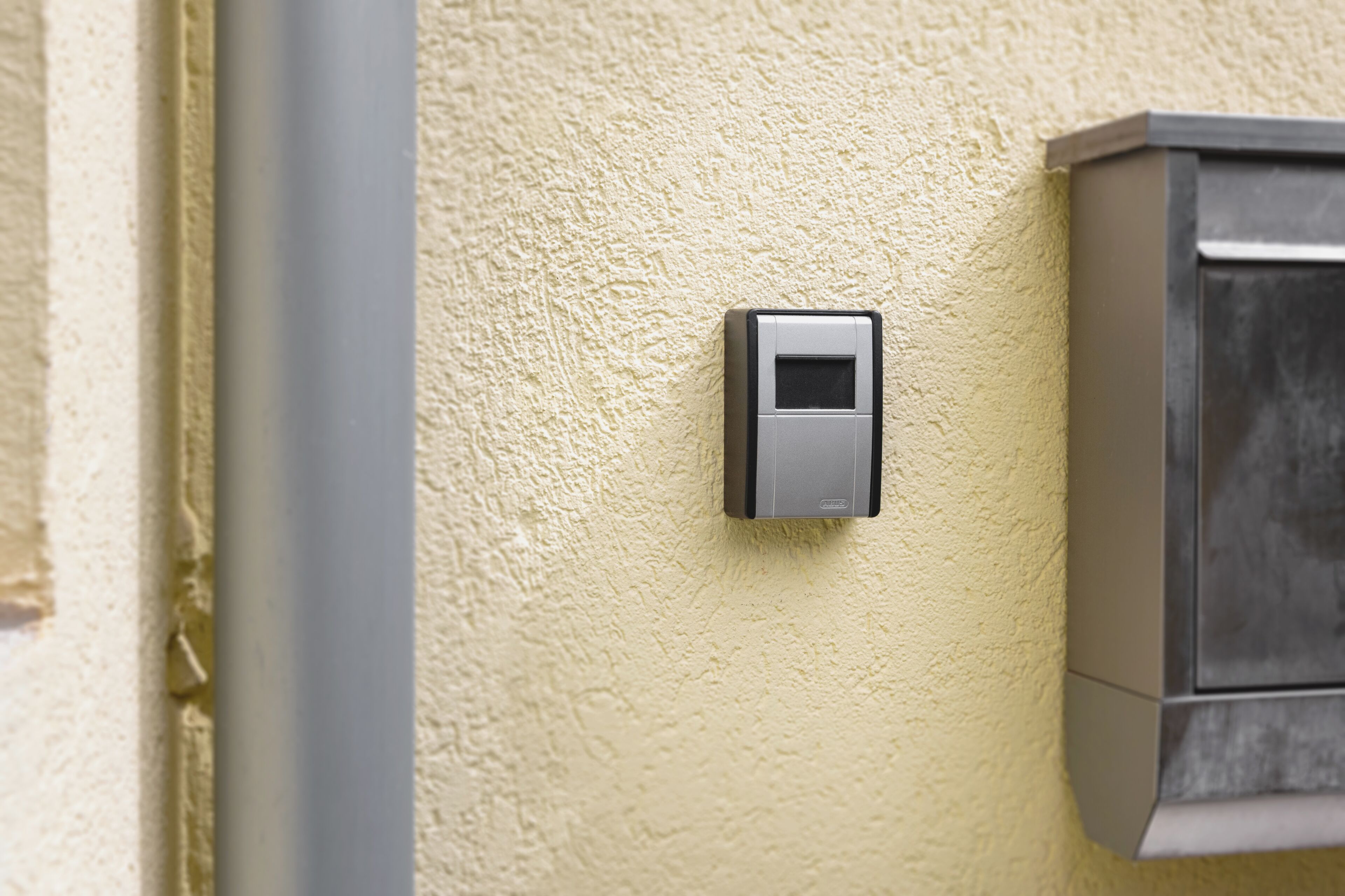 A wall-mounted intercom device on a textured wall.