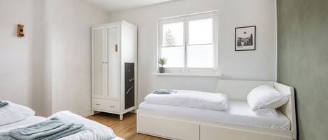 A bedroom with a bed, a wardrobe, a window, and a wall-mounted picture.