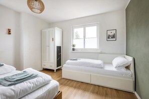 Un dormitorio con una cama, un armario, un ventanal y un cuadro colgado en la pared.