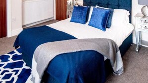 Une chambre à coucher avec un grand lit, une tête de lit, des tables de chevet et un luminaire au plafond.