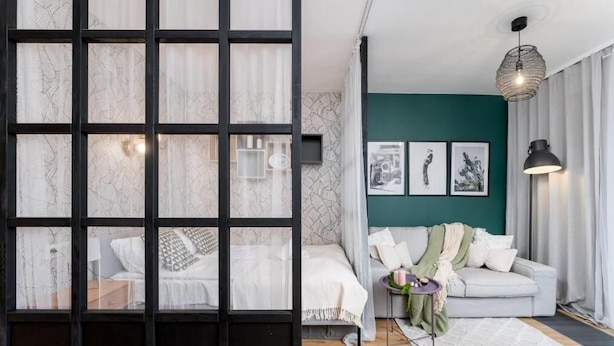 A modern bedroom with a large window, a bed with white bedding, a bedside table, and a nightstand. - Malila Apartments Plac Bohaterów Getta (Kraków)