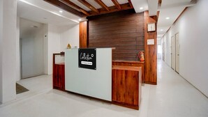 A reception area with a wooden reception desk, a sign indicating it's a company-serviced collection point, and a wooden wall behind the desk. - Collection O Warje Pune Guest House (Pune)