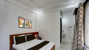 A hotel room with a bed, a nightstand, a bathroom with a sink, and a shower. - Collection O Warje Pune Guest House (Pune)