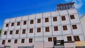 A multi-story building with a white facade and brown-framed windows. - Collection O Warje Pune Guest House (Pune)