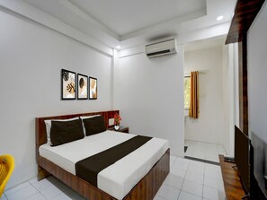 Een hotelkamer met een houten bed, witte muren en een airconditioner aan het plafond.