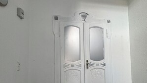 Une pièce dotée d’une porte à deux battants, d’un interrupteur et d’un paillasson.