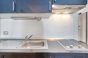 A modern kitchen with a stainless steel sink, a built-in stove, and blue cabinets.