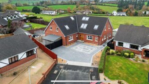 A residential area with houses, a large driveway, and a green field in the background. - Cosy independent studio in a small village with countryside views (Richhill)