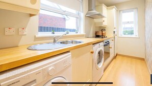 A compact kitchen with a built-in dishwasher, a stove, and a window providing natural light. - Cosy independent studio in a small village with countryside views (Richhill)